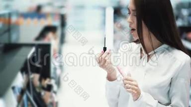 年轻漂亮的女人在化妆品店里选择口红，试着涂在嘴唇上
